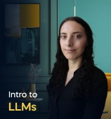 The Intro to LLMs course creator stands in a modern office setting with the text 'Intro to LLMs' on the left side of the image.