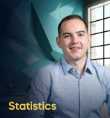 The Statistics course creator stands in a modern office setting with the text 'Statistics' on the left side of the image.