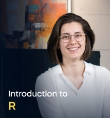 The Introduction to R Programming course creator stands in a modern office setting with the text 'Introduction to R Programming' on the left side of the image.