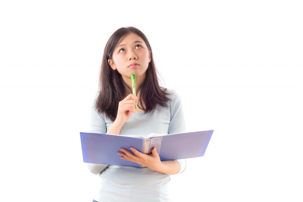 Asian woman with purple notebook thinking with a pen up to her chin